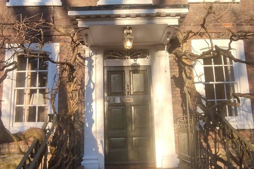 A building with a dark wooden door, white columns, and a lantern above the door. 1