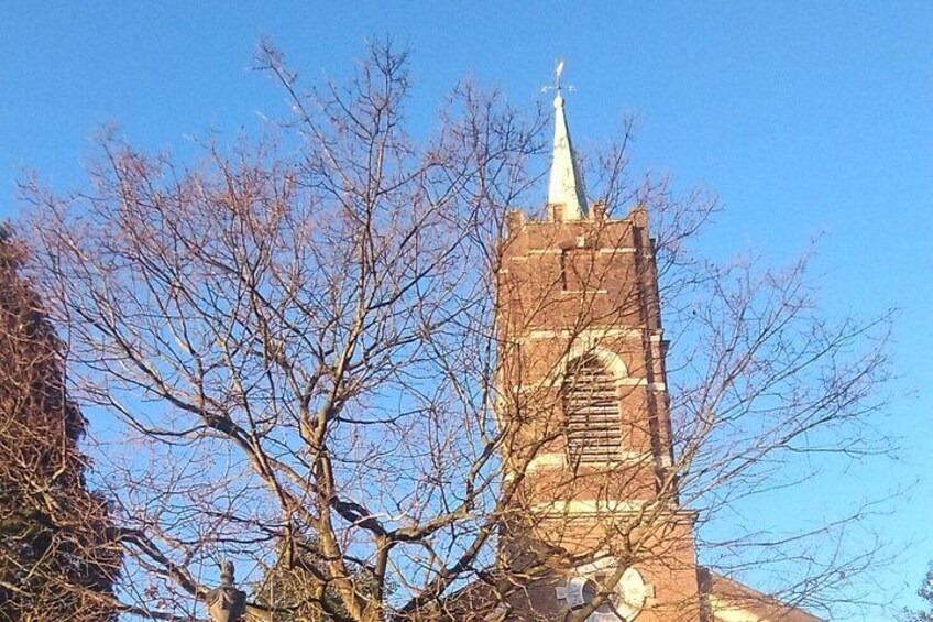 A brick church tower with a spire, surrounded by leafless trees. 5