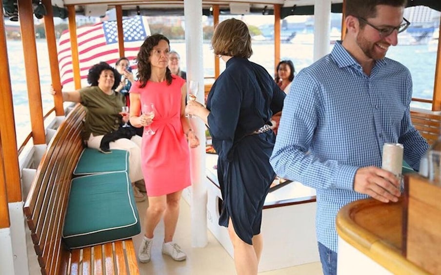 A group of people on a boat with a wooden deck and green cushioned seats. 2