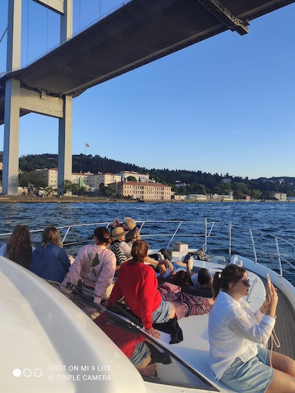 A group of people on a boat near a bridge and buildings in the background. 3