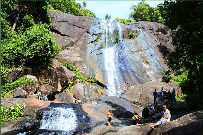 A waterfall cascading over large rocks surrounded by greenery. 5