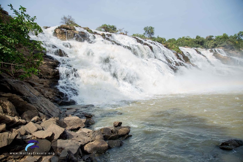 A waterfall cascading over rocks into a river, surrounded by greenery. 3