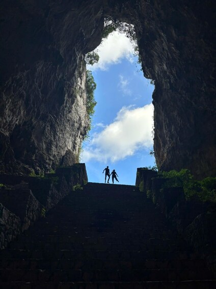 A cave opening with two people silhouetted against the sky. 2
