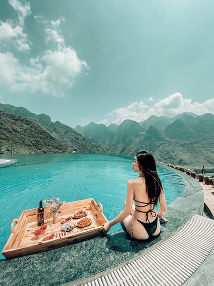 A woman sitting by a pool with mountains in the background. 3