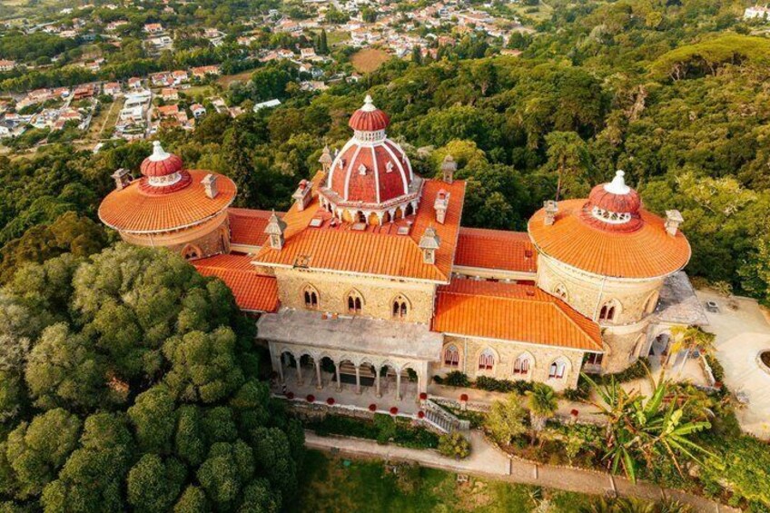 An aerial view of a large, ornate building with domed roofs surrounded by lush greenery. 5