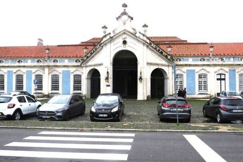 A building with a red-tiled roof and blue accents, a parking lot with several cars, and a pedestrian crossing. 3