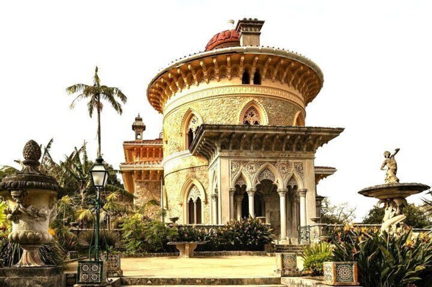 A historic building with ornate architecture, including a dome and columns, surrounded by tropical plants and statues. 4