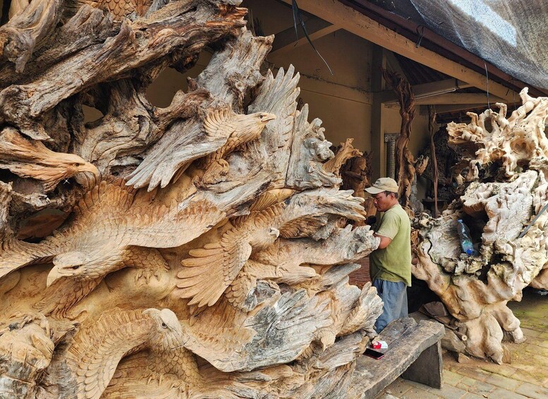 A person examining large, intricately carved wooden sculptures. 5