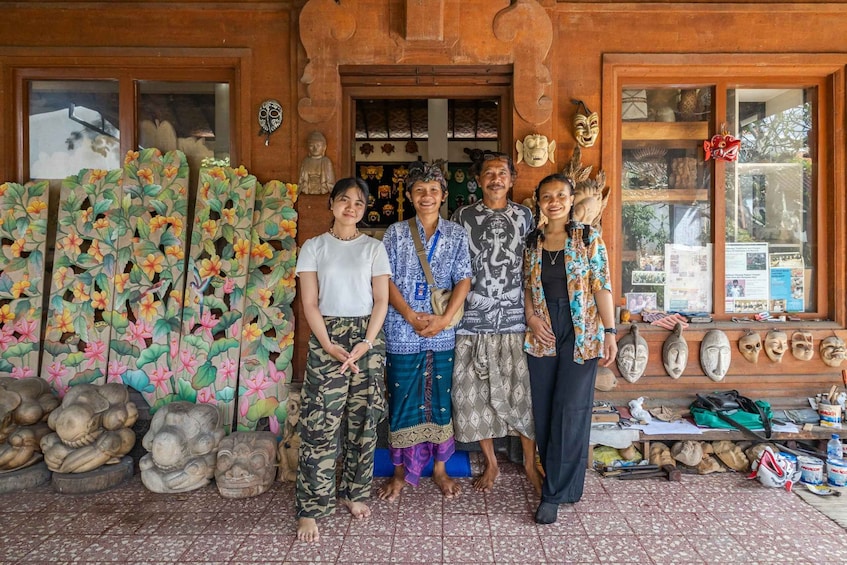A group of people standing in front of a shop with wooden carvings and masks on display. 2
