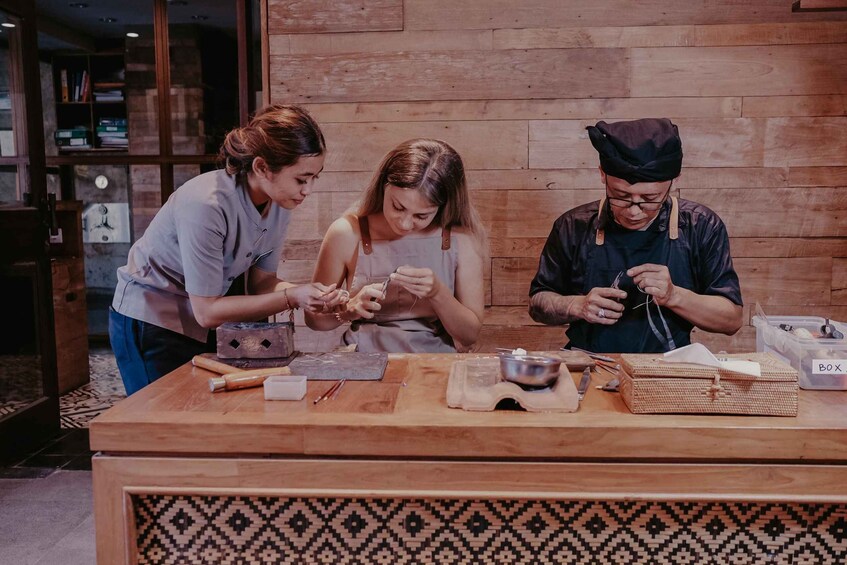 Three people working on a craft project at a wooden table with tools and materials. 5
