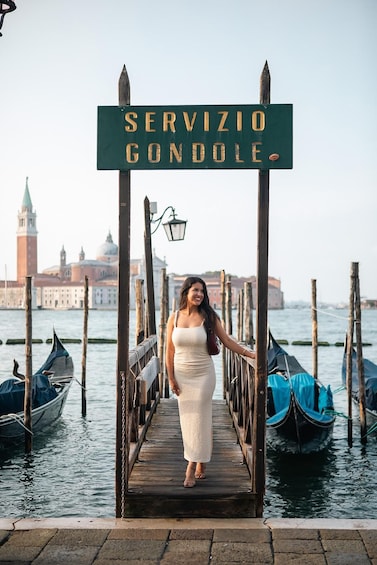 Nainen seisoo puisella sillalla Venetsiassa, ja sillalla on kyltti, jossa lukee: ”SERVIZIO GONDOLLE”. 2