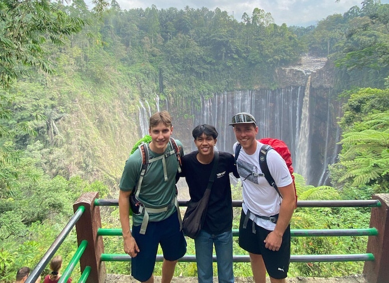 Three people standing on a viewing platform with a waterfall in the background. 5