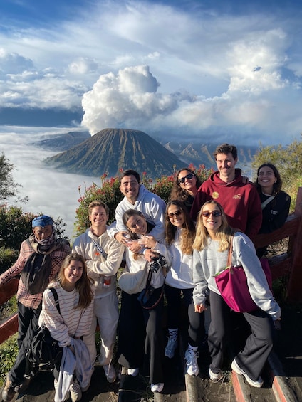 A group of people posing in front of a mountain with a cloud formation. 1