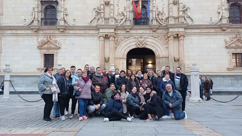A group of people posing in front of a historic building with ornate architecture. 2