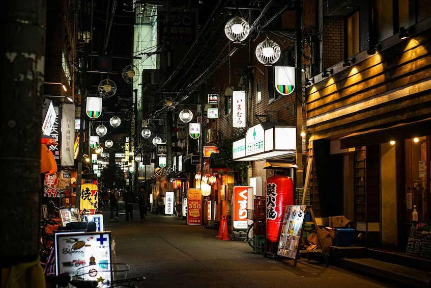 A narrow street at night with illuminated signs and lanterns. 3