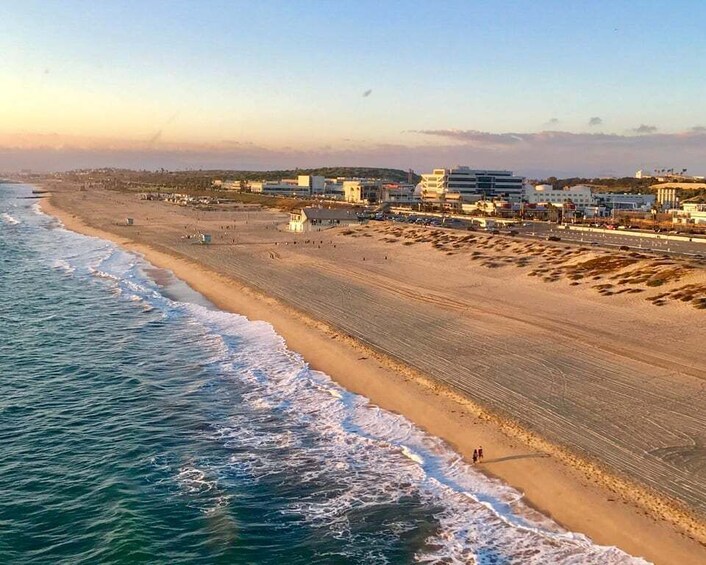A beach with waves, buildings, and a clear sky. 1