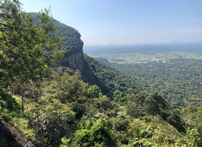 A mountainous landscape with dense green vegetation and a clear view of the valley below. 2