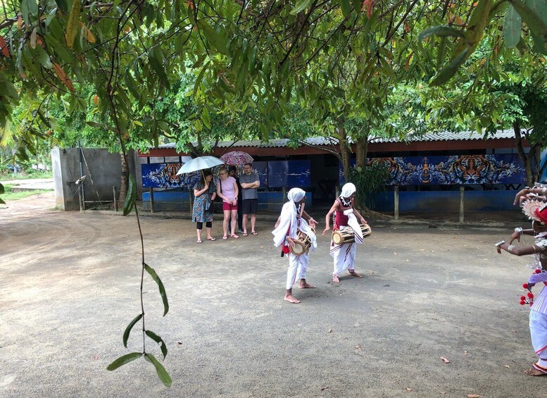 A group of people in traditional attire performing near a mural. 3