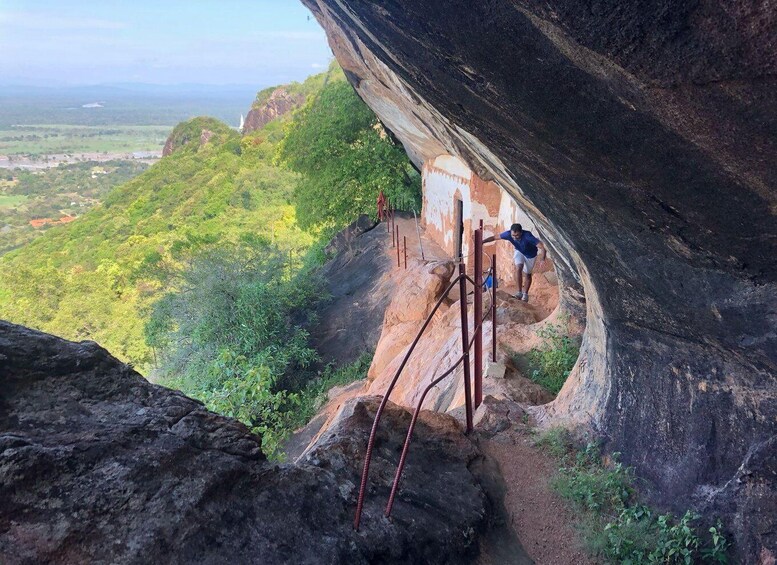 A person climbing a rocky cliff with a narrow ledge. 4