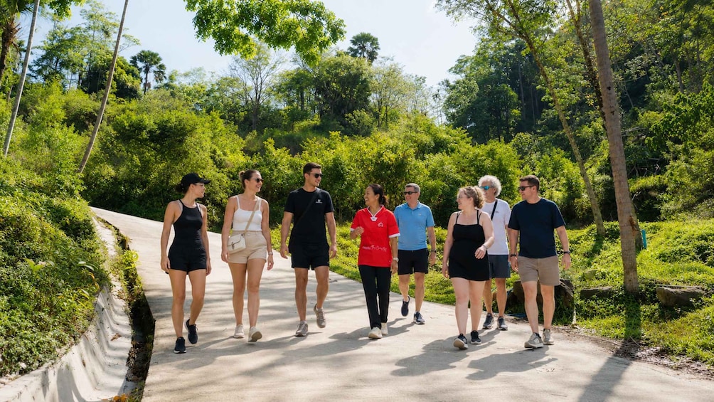 A group of people walking on a concrete path surrounded by greenery. 2