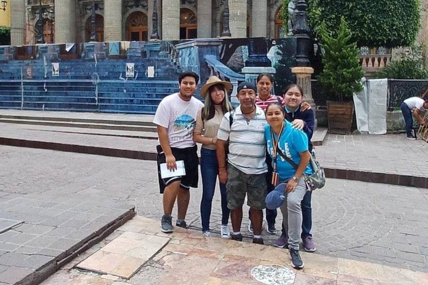 A group of people posing in front of a fountain with steps and a building in the background. 5