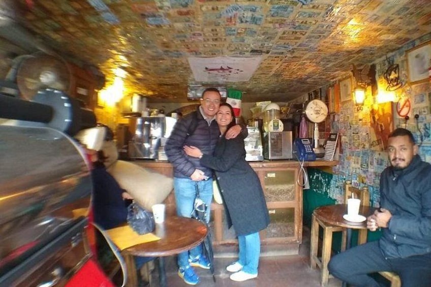 A bar with people, a counter, and a wall with posters. 4