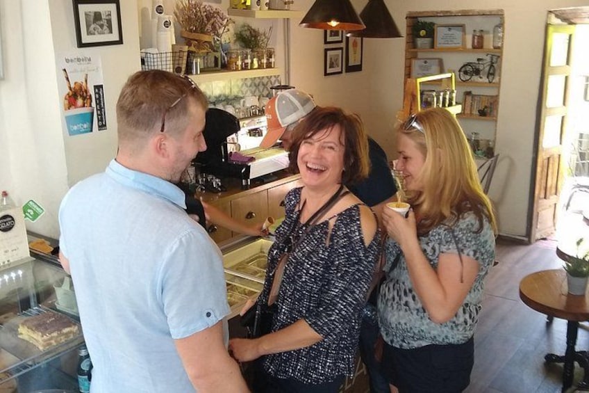 A group of people in a cafe with a counter, shelves with items, and a bicycle in the background. 5