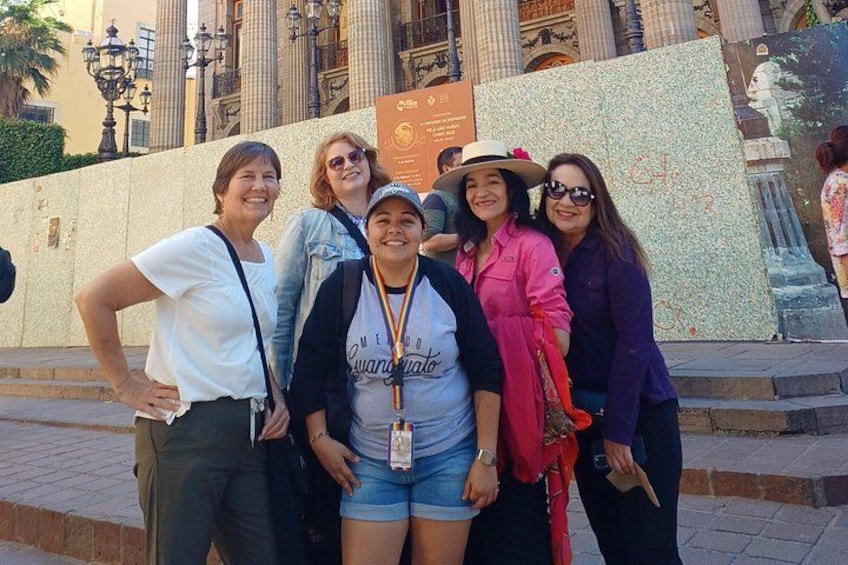 A group of people posing in front of a historical building with columns and a fountain. 3
