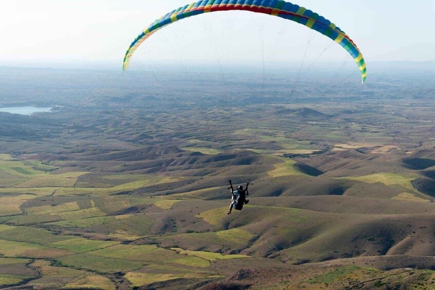 A person paragliding over a hilly landscape. 5