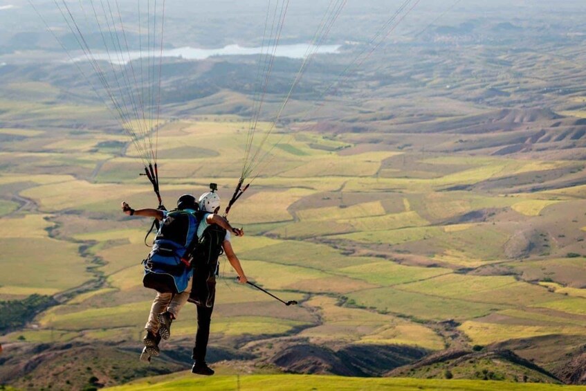 A person paragliding over a hilly landscape. 2