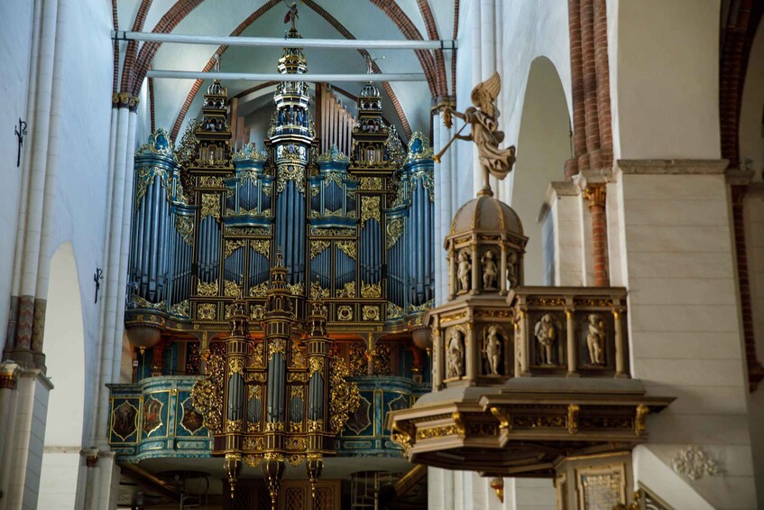 An ornate organ with blue and gold detailing inside a church. 1