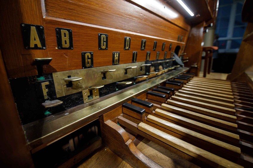 A pipe organ with wooden keys and metal pipes labeled with letters A to G. 2