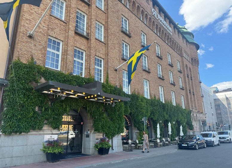 A historic brick building with a green ivy-covered facade, a large flag, and outdoor seating. 4