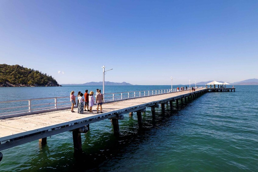 A pier extending into a calm body of water with people walking along it. 1
