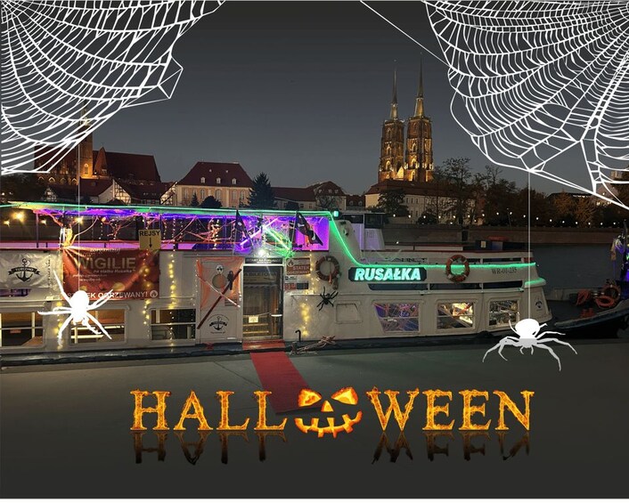 A Halloween-themed boat with illuminated decorations and spider webs, docked near a historic cathedral. 1