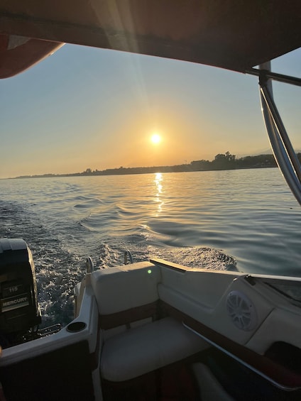A boat on calm water with the sun setting in the background. 3