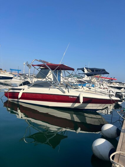 A red and white boat docked at a marina with other boats in the background. 2