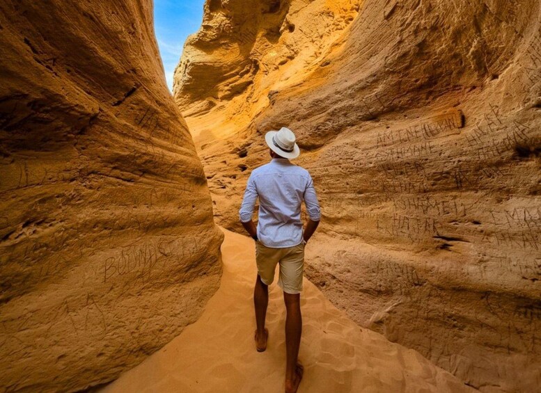 A person walking through a narrow canyon with rock walls. 2