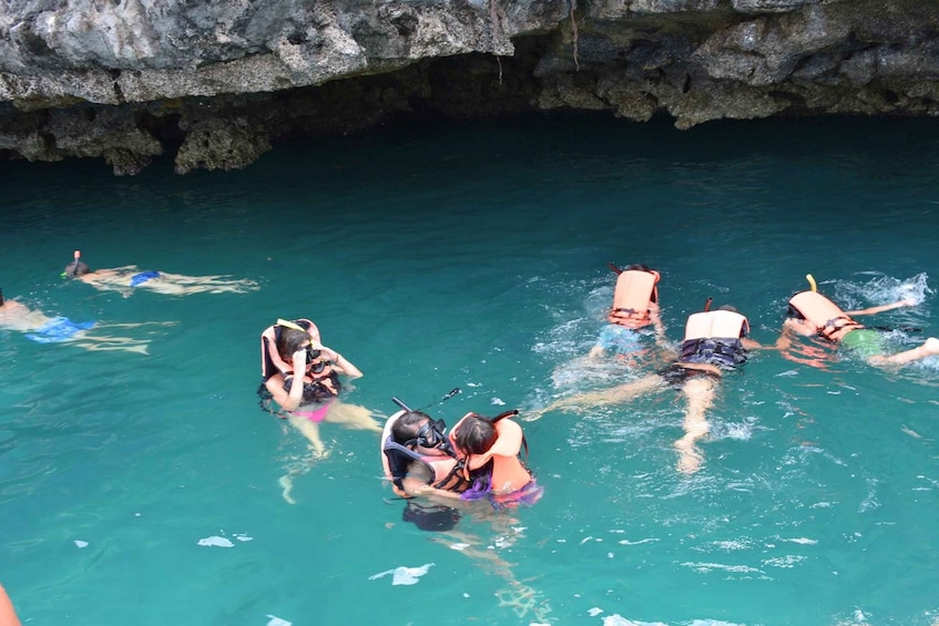 A group of people swimming in a clear blue pool with rocky formations in the background. 5