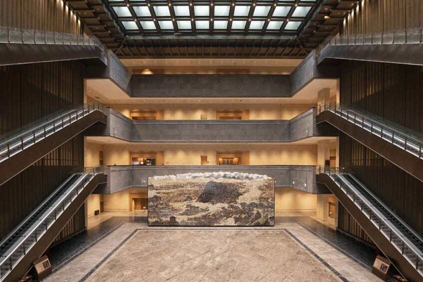 A modern building with multiple floors, glass ceiling, and a large central artwork. 3