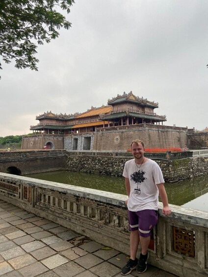 A person standing on a bridge with a traditional building in the background. 3