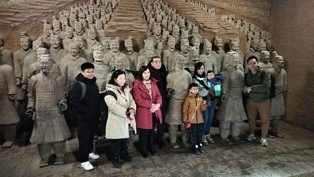 A group of people standing in front of a large stone sculpture of soldiers. 2