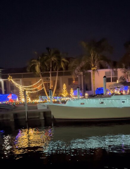 A boat docked at a marina with festive lights and palm trees in the background. 2