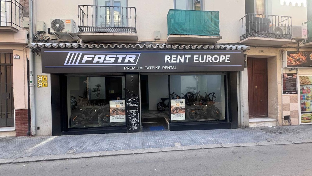A storefront with a sign for 'FastR Premium Fatbike Rental' and a 24-hour service notice. 2