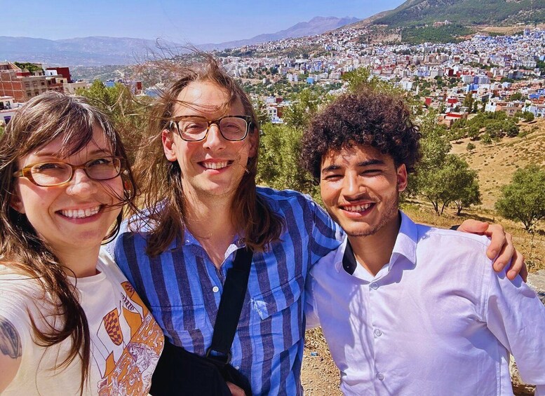 Three people standing with a cityscape and mountains in the background. 2