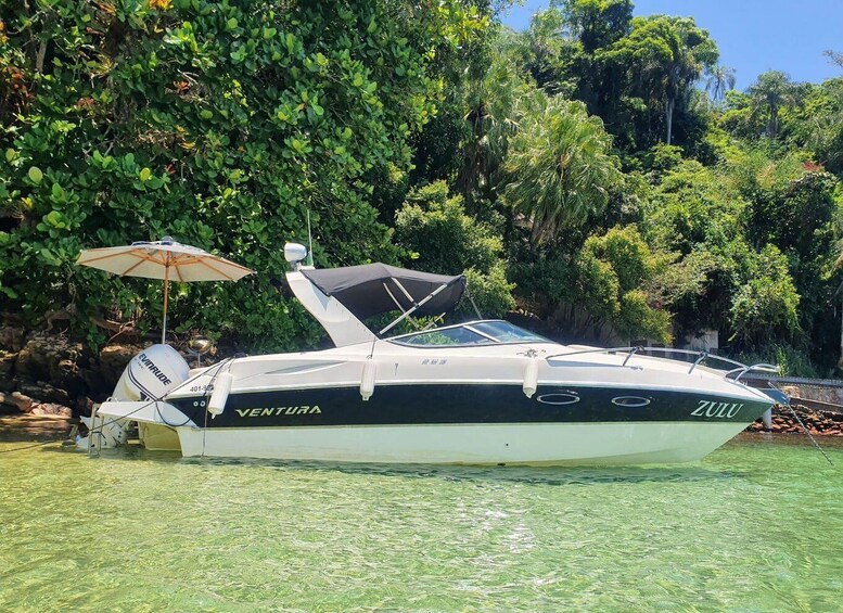 A white and black boat named 'VENTURA' docked in clear water with an umbrella nearby. 4