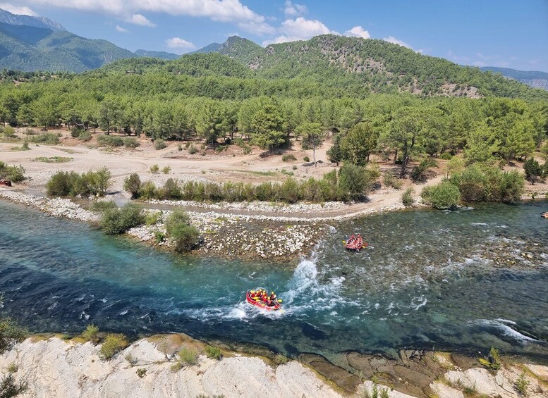 A river with clear water, surrounded by rocky terrain and dense green forest. 5
