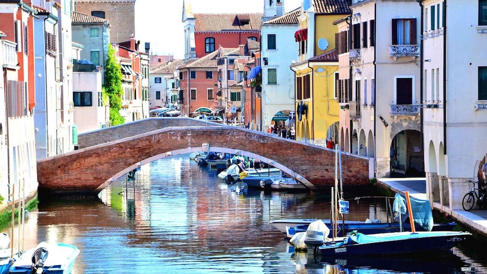 A canal with boats, a stone bridge, and colorful buildings. 1