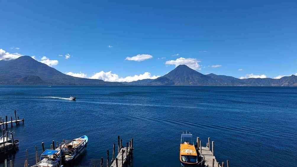 A boat docked at a pier with mountains in the background. 1