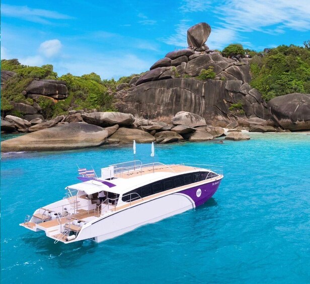 Een boot op turquoise water, met een rotsachtige richel op de achtergrond. 1